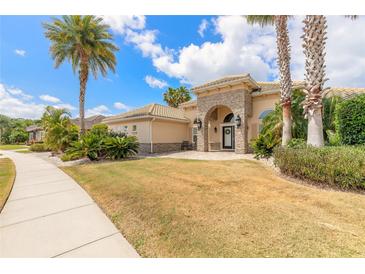 Stunning home exterior with stone accents, arched entryway, lush landscaping, and mature palm trees at 2913 Linari Ct, New Smyrna Beach, FL 32168