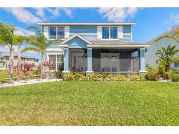 Charming blue two-story home with a screened-in porch, lush landscaping, and a well-manicured lawn at 3136 Portofino Blvd, New Smyrna Beach, FL 32168