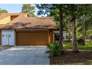 Charming home exterior featuring a brown garage door, well-manicured lawn, and mature trees at 5 Soco Trl, Ormond Beach, FL 32174