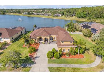 Aerial view of a tan home with a brown roof with a lake in the backyard at 610 Mura Ct, New Smyrna Beach, FL 32168