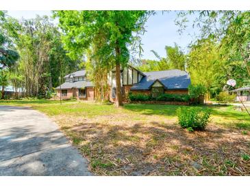 Charming two-story brick home with lush landscaping and mature trees, creating a serene and private setting at 706 S Timberlane Dr, New Smyrna Beach, FL 32168