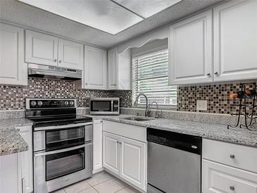 Bright kitchen features white cabinets, stainless appliances, granite counters, and stylish tile backsplash at 95 Moonstone Ct, Port Orange, FL 32129