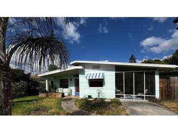Exterior shot of the home, showcasing the facade, screen porch, and mature landscaping under a sunny sky at 114 Hickory St, New Smyrna Beach, FL 32168