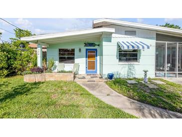 Charming home featuring a quaint blue door, awning, and well-manicured lawn with a stepping-stone walkway at 114 Hickory St, New Smyrna Beach, FL 32168