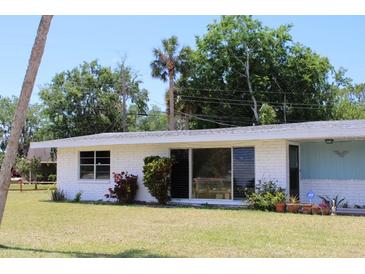 Charming single-story home with white brick exterior and well-maintained lawn at 1830 Needle Palm Dr, Edgewater, FL 32132