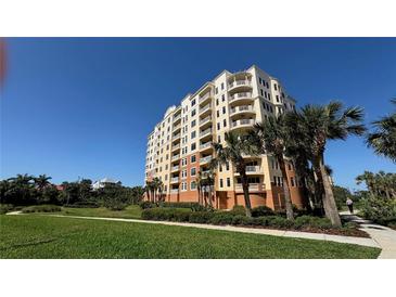 Multi-story condo building featuring multiple balconies surrounded by palm trees, tropical plants, and green lawns at 250 Minorca Beach Way # 206, New Smyrna Beach, FL 32169