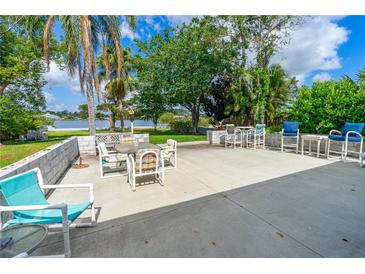 Large back patio with outdoor seating and mature tropical trees and bushes overlooking the water at 2576 Sunset Dr, New Smyrna Beach, FL 32168