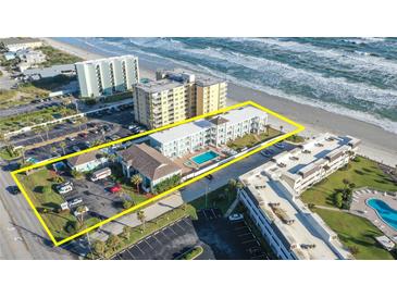 Aerial view of a beachside condo complex featuring a community pool, palm trees, and private beach access at 3509 S Atlantic Ave # 102 And 103, New Smyrna Beach, FL 32169