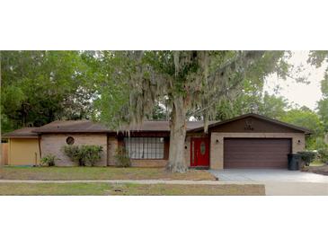 Charming brick home with a well-manicured lawn and a beautiful tree in the front yard at 3736 Paige St, Port Orange, FL 32129