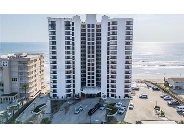 Condo building exterior with ample parking, blue signage, and ocean view from this multi-story condo at 3855 S Atlantic Ave # 1503, Daytona Beach Shores, FL 32118
