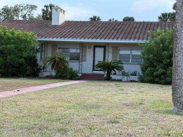 Charming single-story home featuring a classic red-tiled roof and cozy front yard with lush greenery at 5018 Riverside Dr, Port Orange, FL 32127