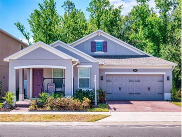 Charming single-Gathering home features a gray exterior, brick driveway, and inviting front porch with seating at 727 Porter Rye Ave, Debary, FL 32713