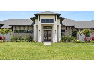 Beautifully landscaped home featuring stone accents and a covered entryway with a black double door at 1624 Turnbull Crossings Dr, New Smyrna Beach, FL 32168