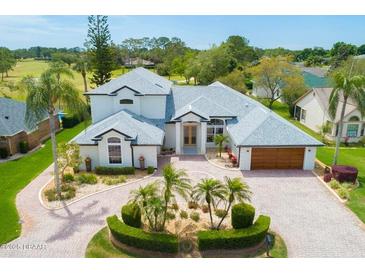 Stunning home featuring a circular driveway, lush landscaping, attached garage, and manicured lawn at 2005 Country Club Dr, Port Orange, FL 32128