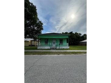 Charming one-story home featuring a porch, green exterior, and well-maintained yard at 306 Sheldon St, New Smyrna Beach, FL 32168
