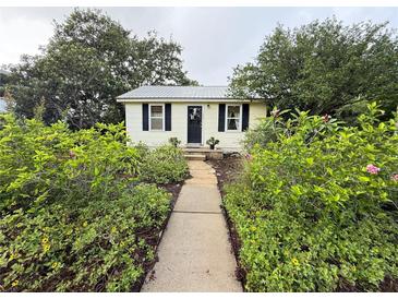 Charming front exterior with lush landscaping, sidewalk, black shutters, and inviting black door at 125 Rio Vista Dr, Edgewater, FL 32132