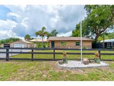 Ranch style home with neutral paint, black fence, and lush greenery at 130 N Gaines St, Oak Hill, FL 32759