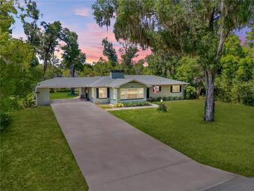 Aerial view of a well-maintained home with an extended driveway and a lush green lawn at 200 W Washington Ave, Deland, FL 32720