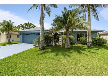 Charming single-story home with lush green lawn, colorful flowers, and mature palm trees at 223 Ne Golf Club Dr, New Smyrna Beach, FL 32168