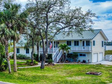 Charming two-story home boasting lush landscaping, a metal roof, and inviting staircases to elevated porches at 2950 Sunset Dr, New Smyrna Beach, FL 32168