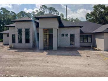 An impressive single-story house featuring a modern design and dark-trimmed windows is still under construction at 3106 Crossing Pine Ln, New Smyrna Beach, FL 32168