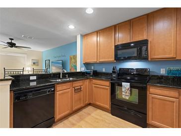 Well-equipped kitchen with wood cabinets, black appliances, and granite countertops at 511 Mount Olympus Blvd, New Smyrna Beach, FL 32168