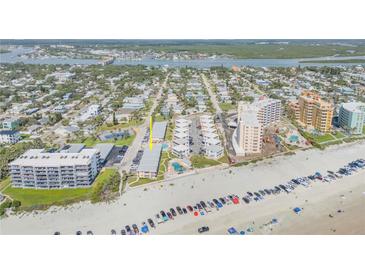Wide aerial view of a beachfront condominium complex with ocean views, tennis courts, and community pool at 525 N Atlantic Ave # 39, New Smyrna Beach, FL 32169