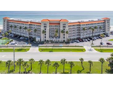 Expansive beachfront condo building featuring a tennis court, palm trees, and covered parking at 5501 S Atlantic Ave # 4090, New Smyrna Beach, FL 32169