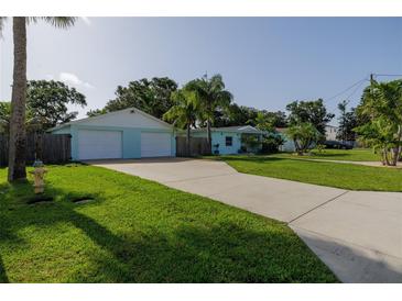 Charming exterior view of light blue home, showcasing a well-manicured lawn, driveway, and a two-car garage at 653 Goodwin Ave, New Smyrna Beach, FL 32169