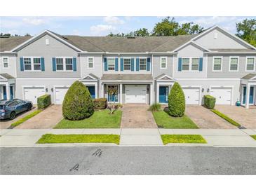 Charming townhomes featuring gray siding, blue shutters, well-manicured lawns, and individual garages at 1453 River Rock Ct, Oviedo, FL 32765
