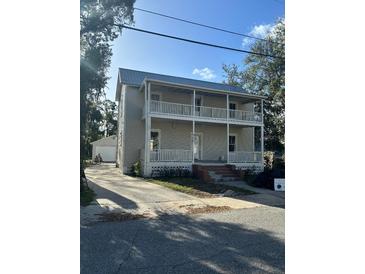 Two-story home featuring double porches, neutral siding, and a metal roof at 306 Murray St, New Smyrna Beach, FL 32168