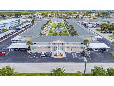 Aerial view of waterfront condo building with lush landscaping, boat docks, and ample parking at 335 N Causeway # E3, New Smyrna Beach, FL 32169