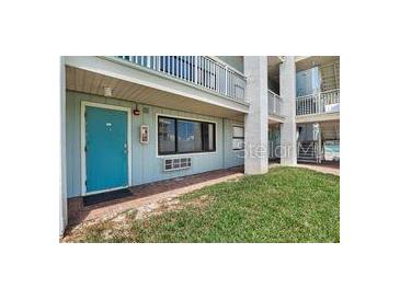 Exterior of condo with grassy area and a teal front door with one window that is open at 3509 S Atlantic Ave # 109, New Smyrna Beach, FL 32169