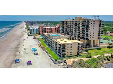 Stunning aerial view of a beachside resort with a pool, tennis court and direct beach access at 4139 S Atlantic Ave # B508, New Smyrna Beach, FL 32169