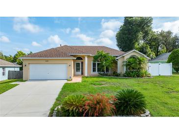 Charming single-story home featuring a well-manicured lawn, complemented by lush landscaping and a two car garage at 505 Sandale Ct, Deland, FL 32724