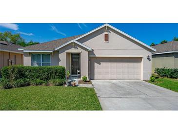 Charming home featuring a well-maintained lawn, inviting entrance, and a two-car garage under a sunny, blue sky at 518 Safe Harbor Dr, Edgewater, FL 32141