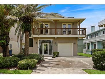 Two-story home with a balcony, garage, and a front yard featuring lush landscaping and mature palm trees at 6956 Turtlemound Rd, New Smyrna Beach, FL 32169