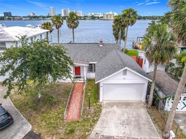 Charming waterfront home with a brick walkway, attached garage, and a view of the bay and city skyline at 255 Lexington Dr, Daytona Beach, FL 32114