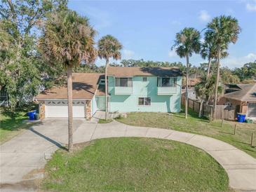 Charming two-story home with circular drive, attached garage, and mature palm trees enhancing the property's curb appeal at 2715 Pine Tree Dr, Edgewater, FL 32141