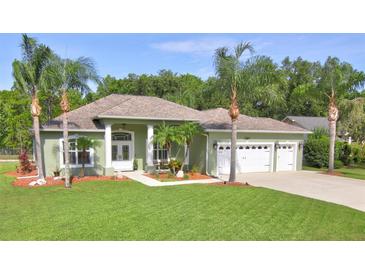 Charming single-story home features a three-car garage, manicured lawn, and mature palm trees at 3288 Spruce Creek Gln, Port Orange, FL 32128
