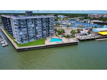 Expansive aerial view of harborside apartment building with swimming pool and boats docked nearby at 101 N Riverside Dr # 1090, New Smyrna Beach, FL 32168