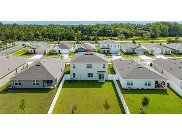 Aerial view of backyard featuring a large, well-maintained lawn and a white fence at 2667 Neverland Dr, New Smyrna Beach, FL 32168