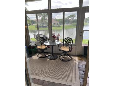 Enclosed patio area with decorative table and chairs overlooking a peaceful pond and lush landscaping at 3552 Casalta Cir, New Smyrna Beach, FL 32168