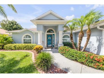 Charming home entrance with blue door, rocking chairs, and lush, colorful landscaping in a well maintained yard at 406 Phillips Creek Ln, New Smyrna Beach, FL 32168