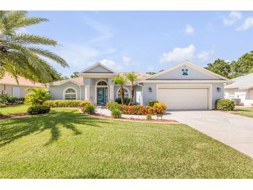 Charming single-story home with manicured lawn, colorful landscaping, and an attached two car garage at 406 Phillips Creek Ln, New Smyrna Beach, FL 32168