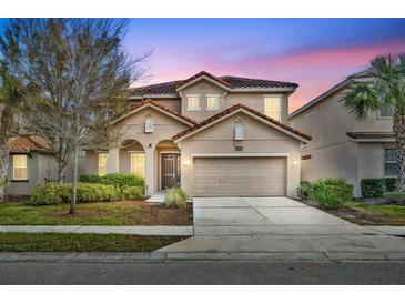 Two-story house with a beige exterior, two-car garage, and landscaping at 5244 Oakbourne Ave, Davenport, FL 33837