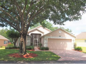 Charming home featuring a lush green lawn, mature trees, and a brick driveway leading to a two-car garage at 3918 Doune Way, Clermont, FL 34711
