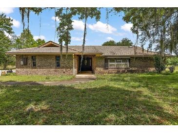 Charming single-story brick home with a tile roof, mature trees, and a spacious front yard at 10290 Buck Rd, Orlando, FL 32817