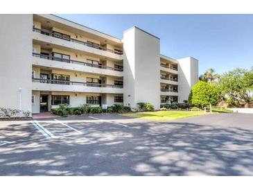 A bright, multi-story condo building with parking, landscaping, and balconies under a clear blue sky at 501 W Old Us Highway 441 # C201, Mount Dora, FL 32757