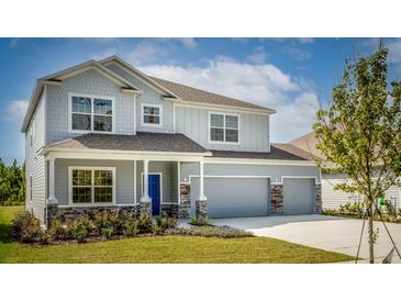 Two-story house with gray siding, stone accents, and a two-car garage at 14 Weston Rd, Leesburg, FL 34748